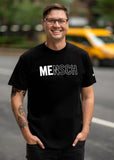A man on the streets of NYC wearing a black shirt that says "Mensch" with the letters "Me" bolded. 