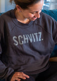 Woman in black crew neck sweatshirt with the word "SHVITZ." printed on the front. 