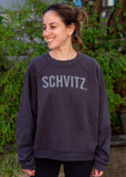 Woman in black crew neck sweatshirt with the word "SHVITZ." printed on the front. 