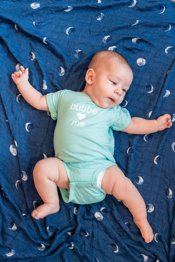 Baby in a green onesie that says 