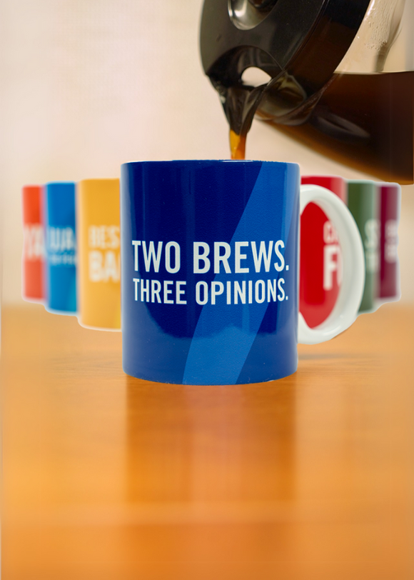 A coffee pot pouring into a blue mug that says "Two Brews. Three Opinions." in white letters. There are 6 other coffee mugs in the background with varied colors and wording. 
